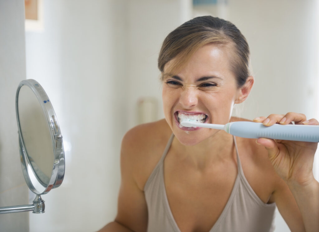 Female aggressively brushing her teeth